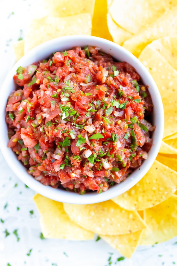 A party bowl full of an easy Mexican salsa recipe that is served with corn tortilla chips.