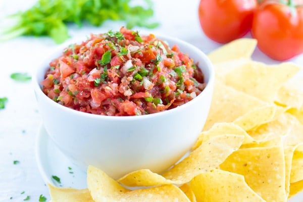 A bowl full of homemade salsa on a party tray with corn tortilla chips for a Cinco de Mayo party.