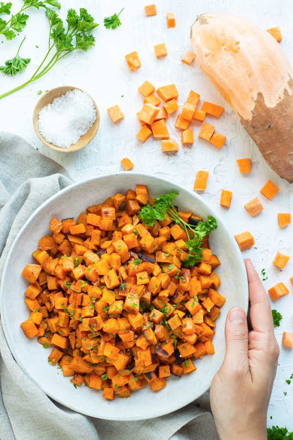 Oven roasted sweet potato cubes in a white bowl.