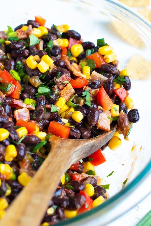 Black bean and corn salsa recipe in a clear Pyrex bowl with bacon.