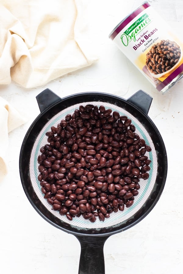 Canned black beans in a mesh strainer.