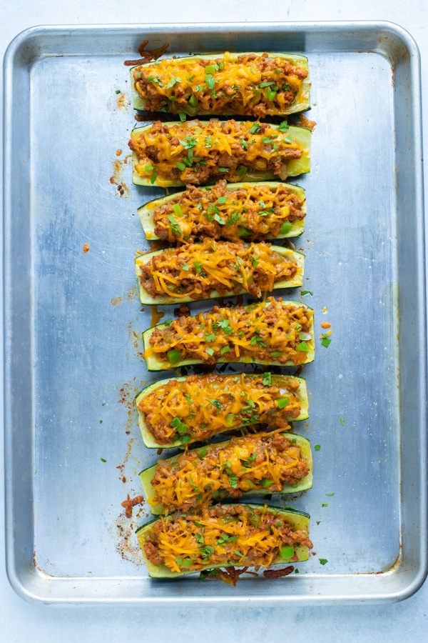 A row of zucchini boats stuffed with ground beef and taco ingredients.