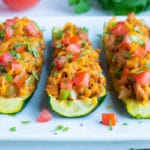 A row of taco stuffed zucchini boats on a dinner platter.
