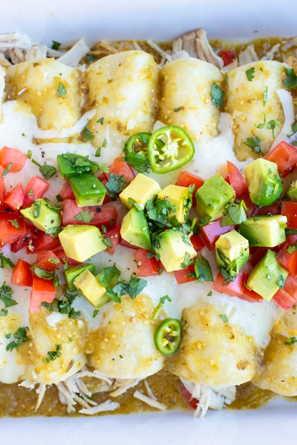 Healthy enchiladas with salsa verde and shredded chicken in a white pan.