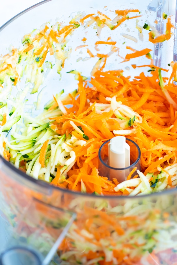 Shredded zucchini and carrots in a food processor.