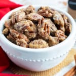 Candied pecans with cinnamon sugar in a white snack bowl for a party.