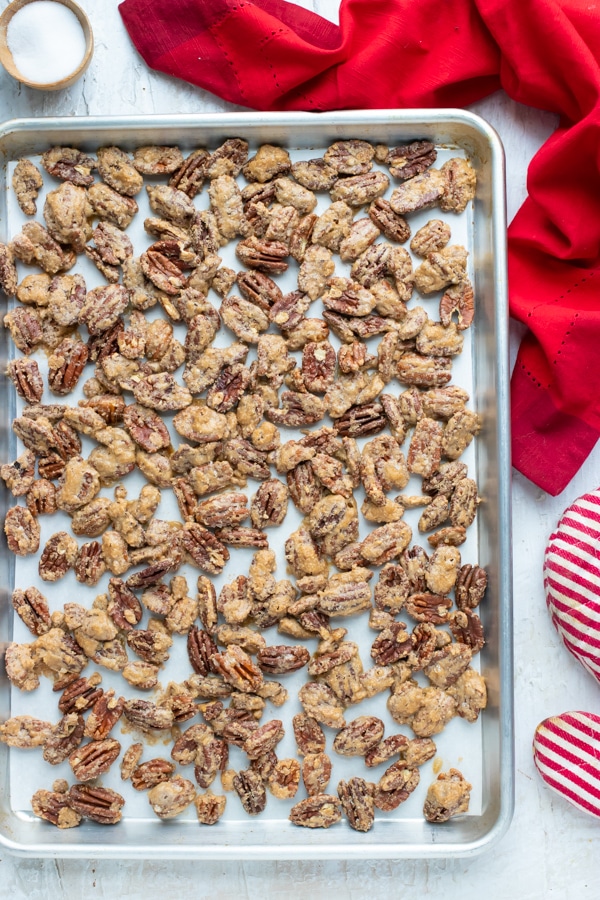 Cinnamon spiced candied pecans that have been roasted in the oven on a large baking sheet.