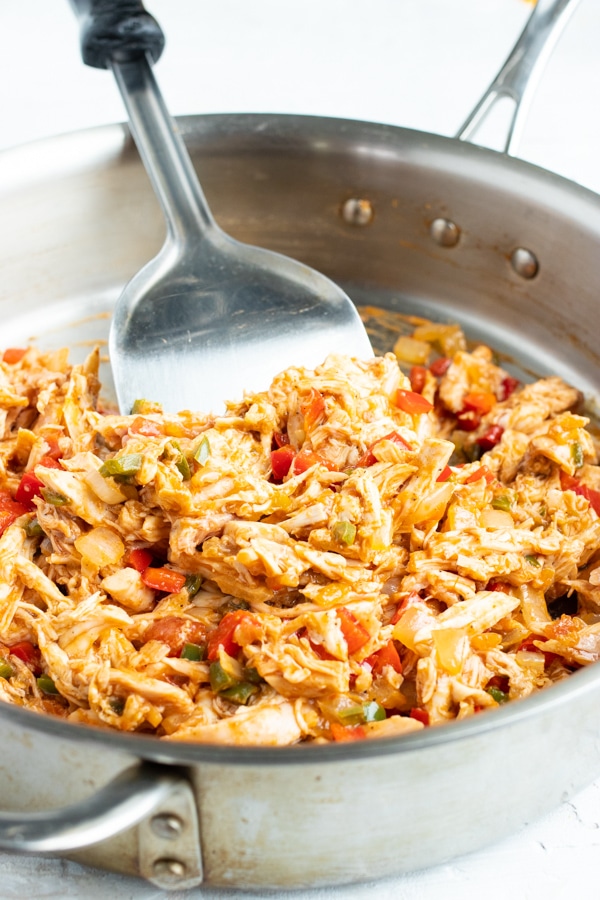 Shredded chicken and salsa in a skillet as the filling for a baked taquitos recipe.