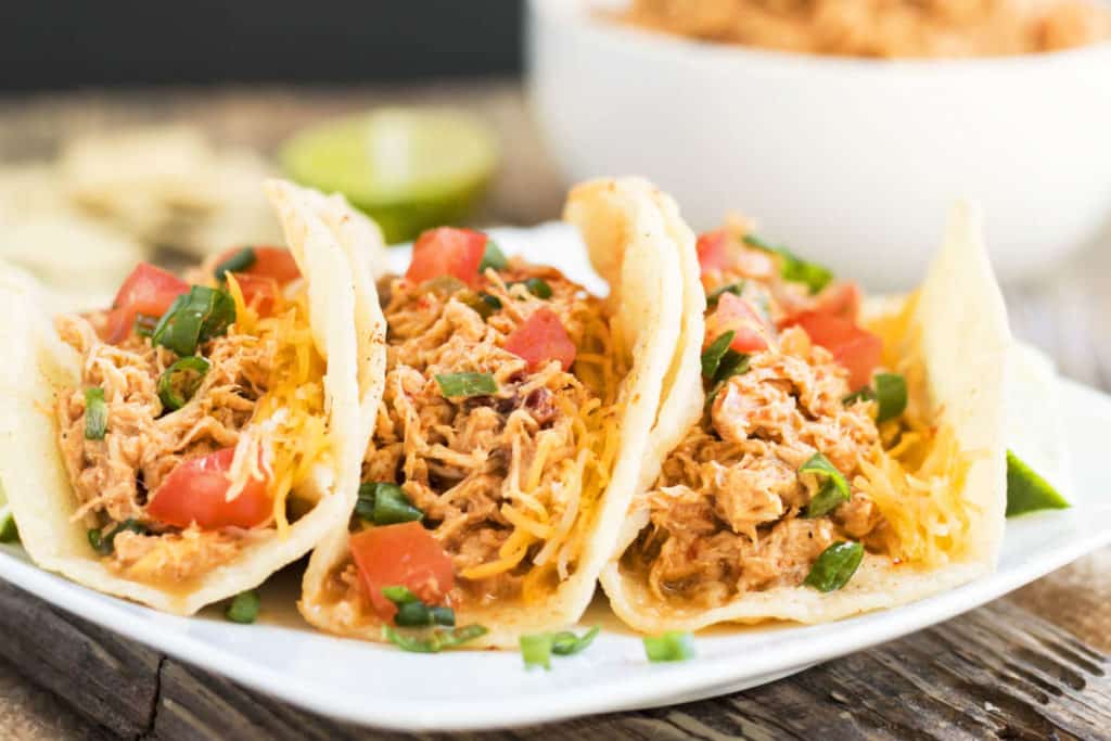 Three tacos on a white plate made with gluten-free shredded salsa chicken for an easy dinner.