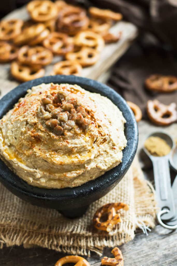Lentil hummus in a bowl surrounded by pretzels for a quick appetizer.