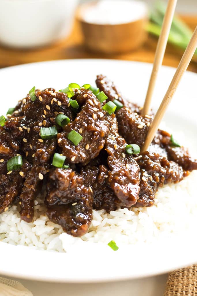 Copycat PF Chang's Mongolian Beef on a bed of rice with chopsticks for lunch.