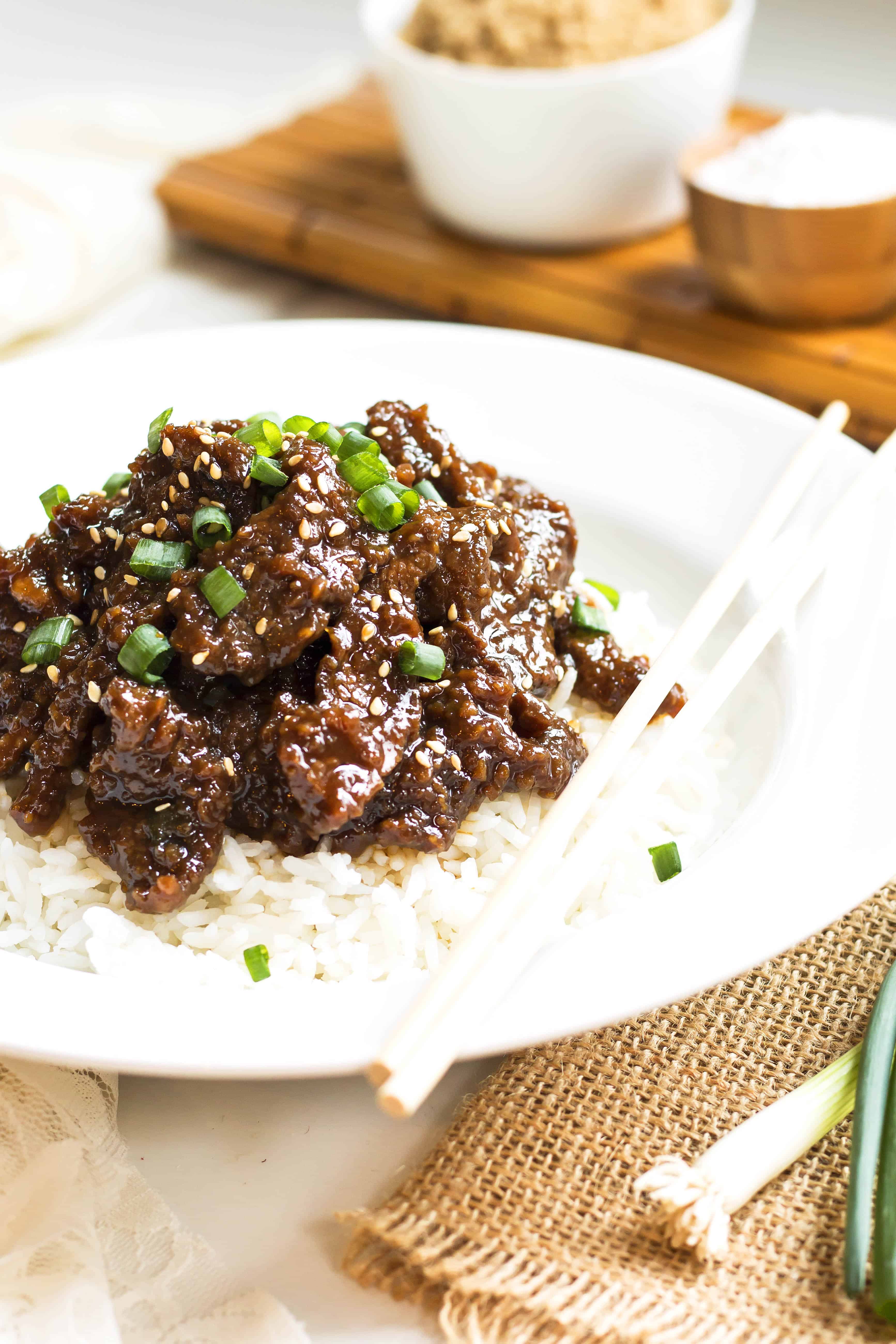 A plate of healthy Mongolian beef on rice with a set of chopsticks for a delicious dinner.