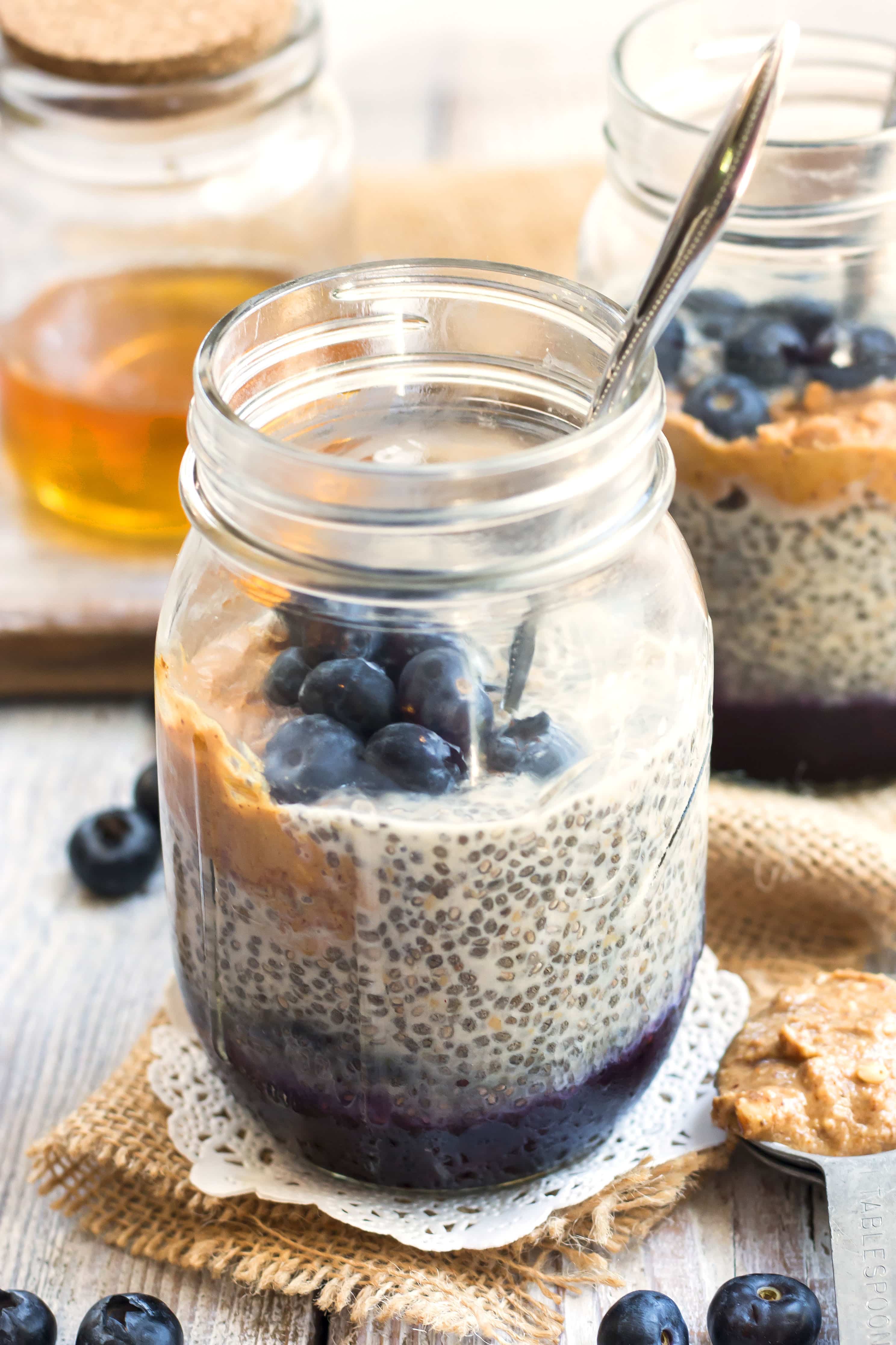 A chia seed pudding recipe inside a jar filled with peanut butter and blueberries for a healthy breakfast.