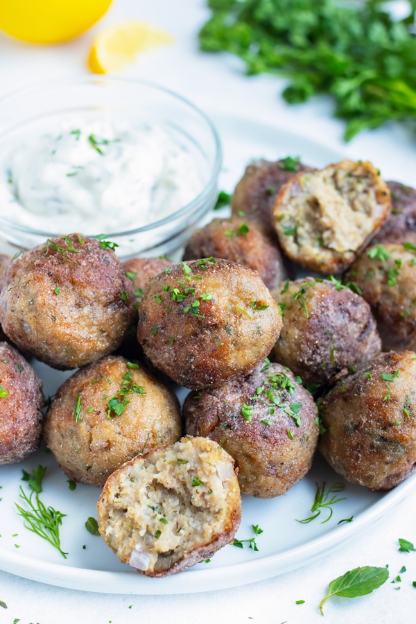 Turkey meatballs are served on a plate to be enjoyed and eaten with a Greek tzatziki dipping sauce.