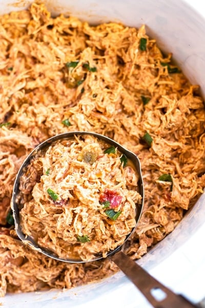 A measuring cup with gluten-free slow cooker shredded chicken made with salsa.