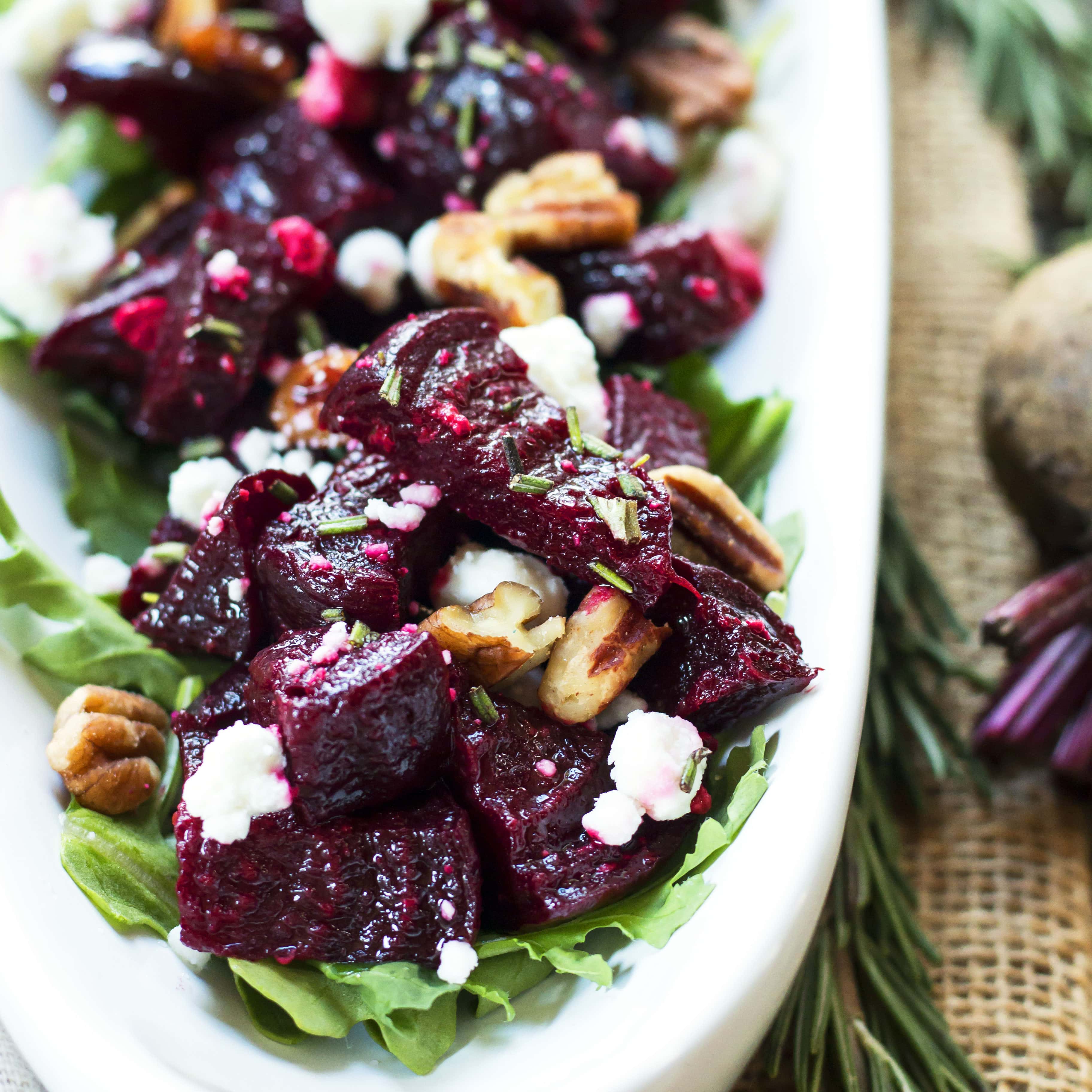 A close-up of caramelized roasted beet cubes with crumbly goat cheese and pecans.