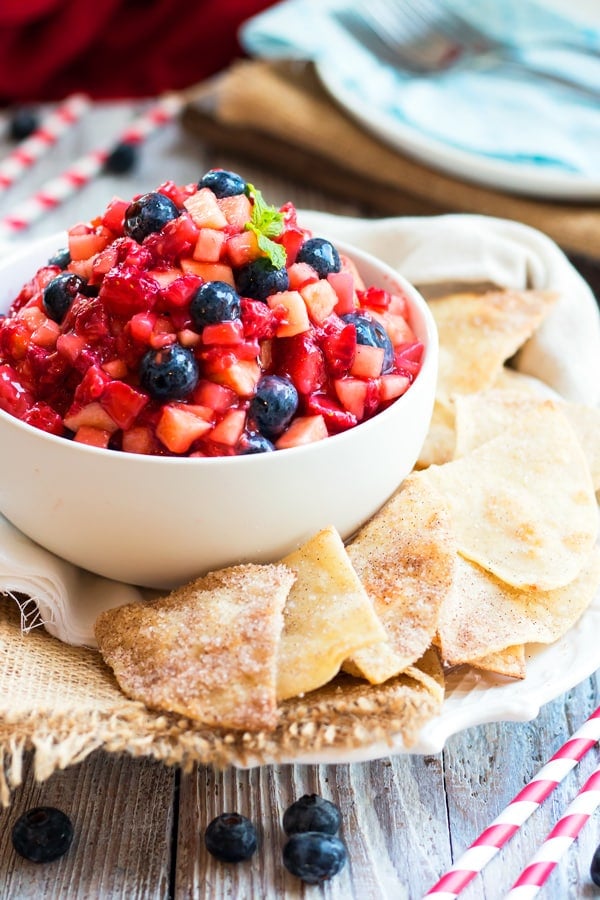 A white bowl of fruit salsa with sopapilla chips on the side for an easy snack.