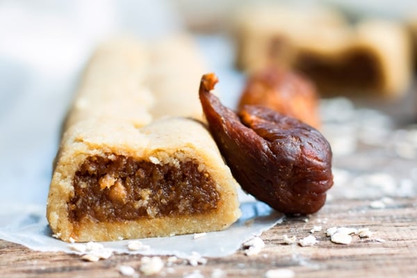 A gluten-free fig newton recipe on a piece of parchment paper with a fig on the side.