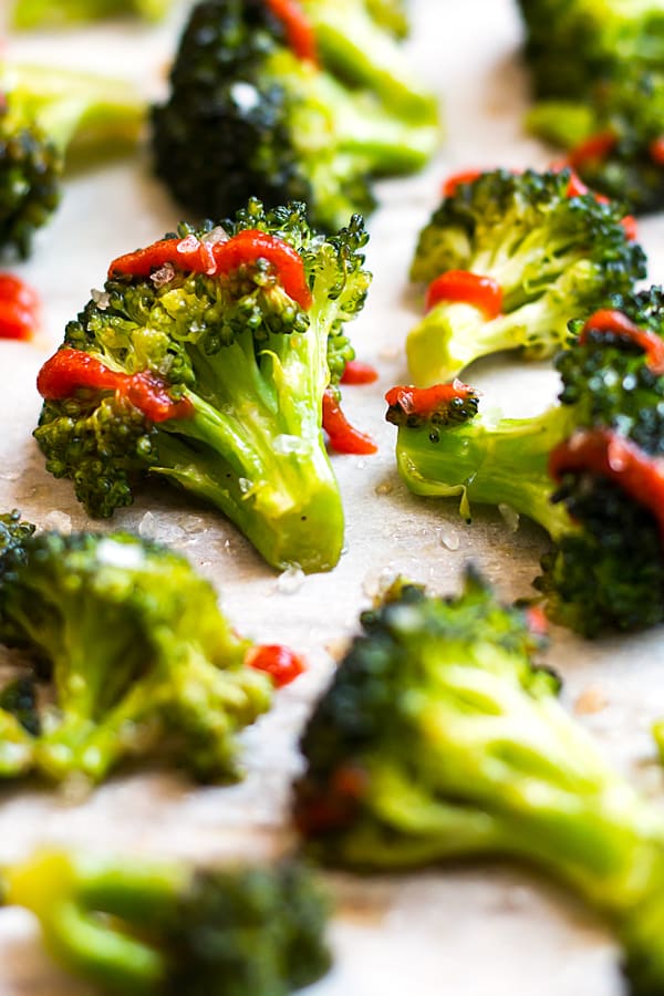 Baked broccoli made with Sriracha and honey on a baking sheet for dinner.