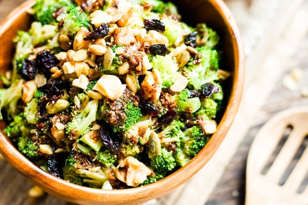 A bowl filled with broccoli cranberry salad with pumpkin seeds and walnuts for a healthy lunch.