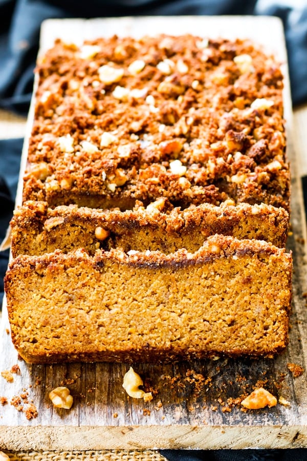 A sliced loaf of gluten-free, healthy pumpkin bread on a piece of wood.