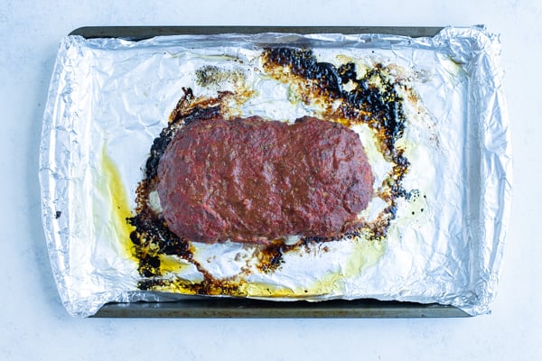 Meatloaf is baked in the oven on a cooking sheet.