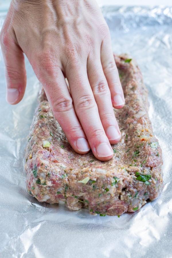 Meatloaf is formed on foil with your hand.