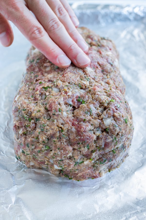 The meatloaf is formed to cover the mozzarella cheese and pesto into a log shape.