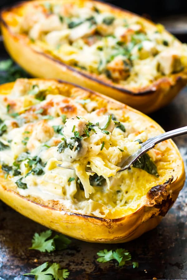 Two Spinach Artichoke Spaghetti Squash Boats filled with chicken for a healthy dinner.