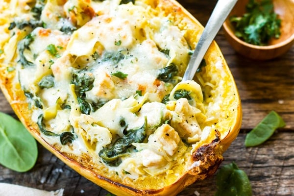 A single squash boat filled with gluten-free spaghetti squash with chicken and spinach.