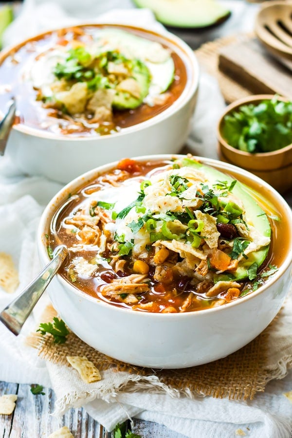 Two white bowls of easy tortilla soup with chicken made in the slow cooker.