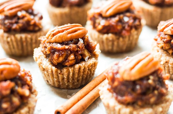 Mini pecan tarts on parchment paper with cinnamon sticks for Thanksgiving dinner.