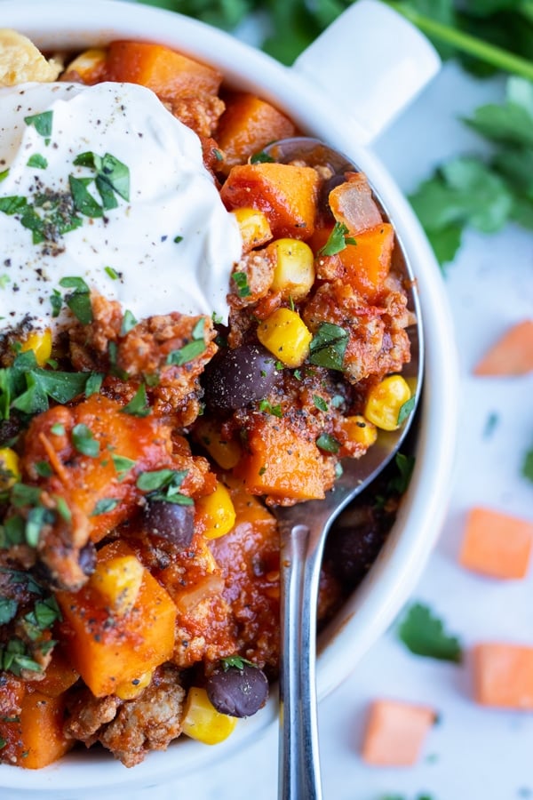 A cozy bowl of ground turkey chili is topped with sour cream for a healthy meal.