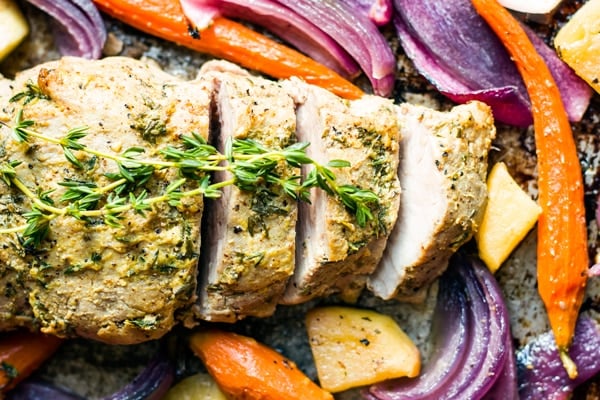 Gluten-free pork tenderloin with apples sliced into four pieces on a baking sheet.