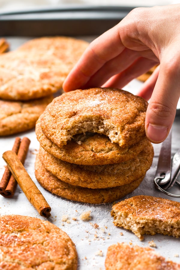 A hand touching a stack of gluten-free Snickerdoodles.