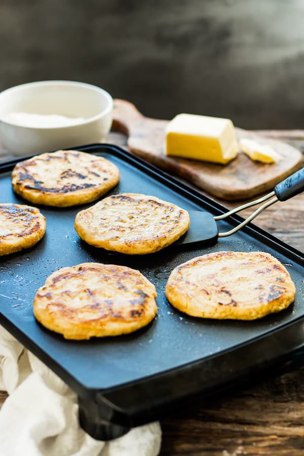 A spatula lifting a gluten-free arepa on a hot plate.