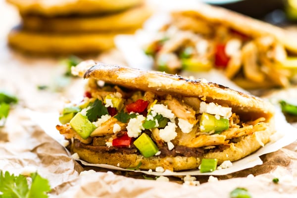 A picture of a gluten-free chicken arepas with chicken, avocado, and vegetables.