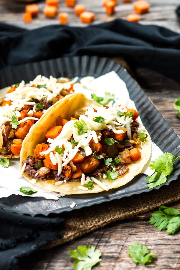 Black Bean & Sweet Potato Tacos | A gluten free and vegetarian taco full of refried black beans, sweet potatoes, cilantro and cheese! They make a great breakfast, lunch or dinner taco recipe.