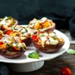 Stuffed baked potato skins made with mozzarella, basil, and tomatoes on a plate ready to serve.