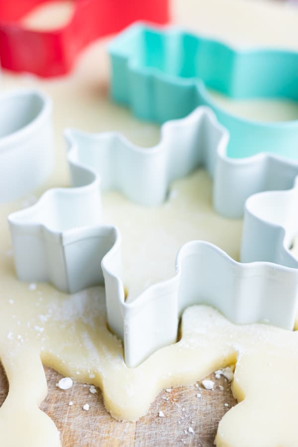 Metal snowflake cookie cutter that is cutting into sugar cookie dough.