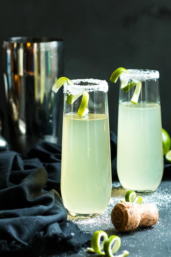 Two glasses filled with Tequila and champagne with a bit of lime.