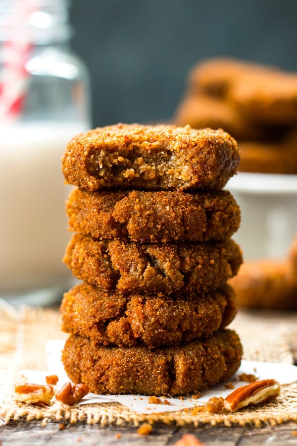 A stack of gluten-free molasses cookies on parchment paper for a holiday treat.