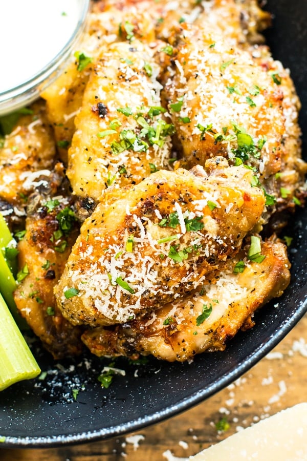 Garlic Parmesan baked chicken wings in a black bowl next to ranch dressing.
