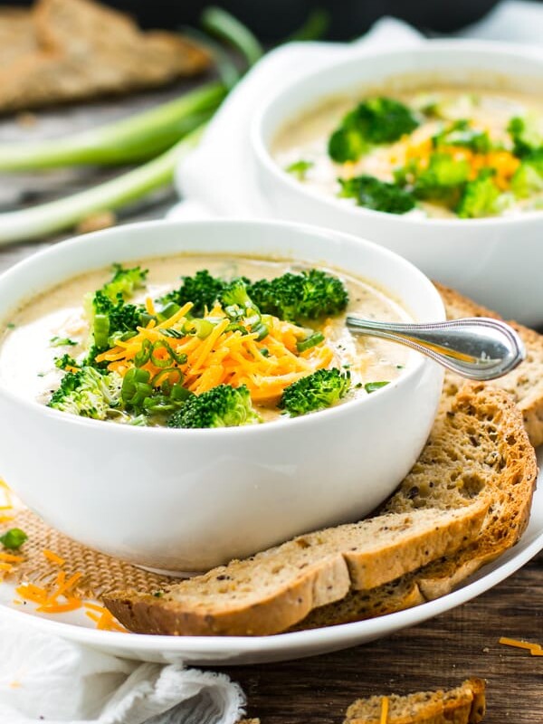 Broccoli cheddar soup in a bowl with garlic bread surrounding it.