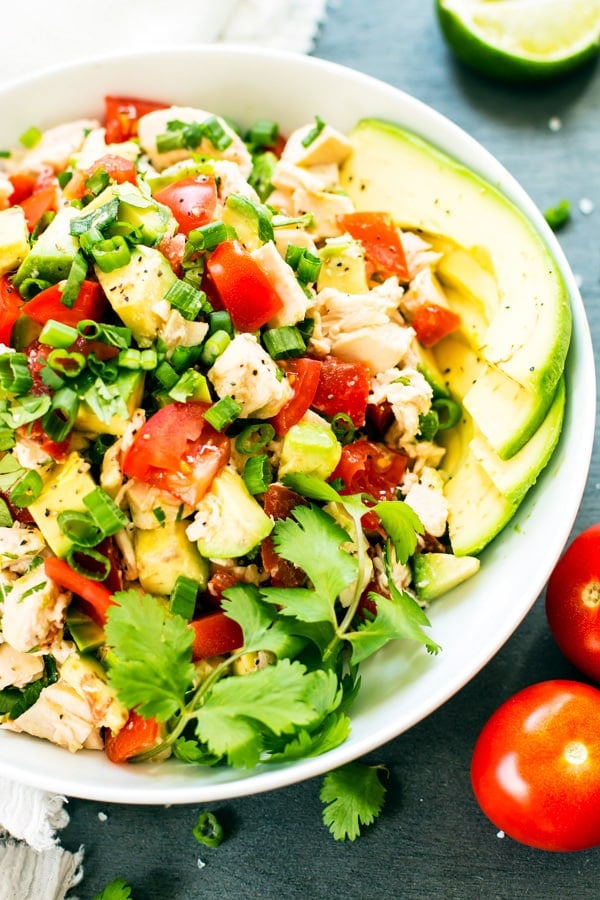 Gluten-free avocado chicken salad recipe in a bowl with tomatoes for a healthy lunch.