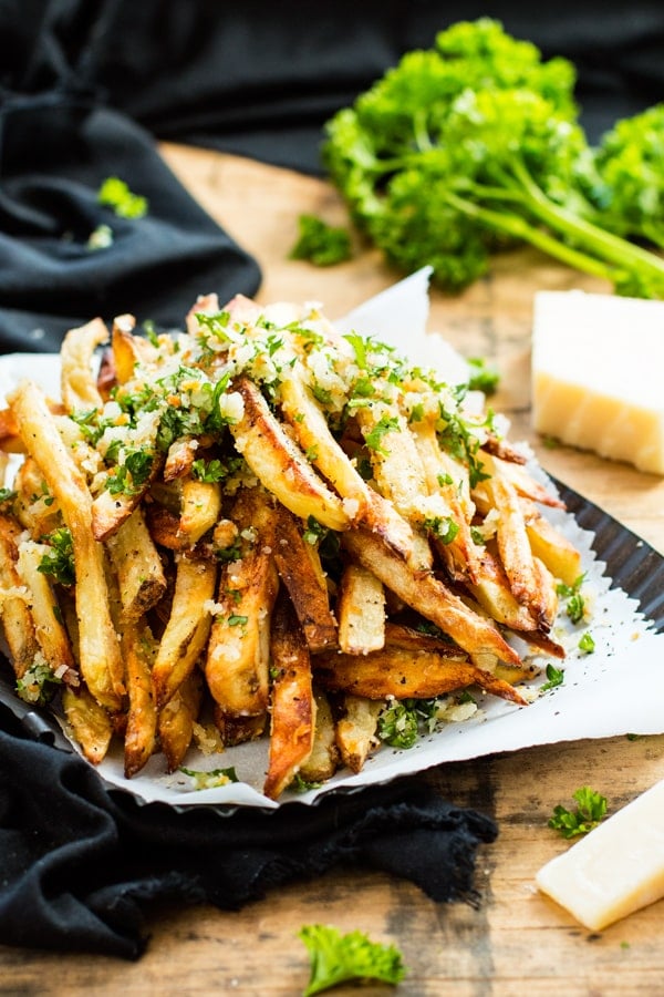Gluten-free garlic fries in a pile on white parchment paper for a delicious side dish.