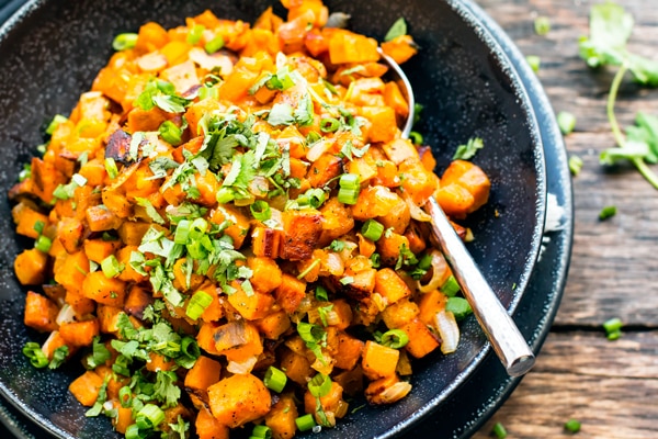 Gluten-free Skillet Sweet Potatoes with Cilantro in a black bowl with a fork for an easy side dish.