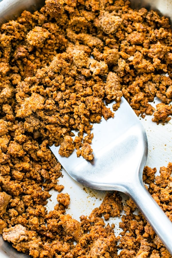 A skillet full of ground turkey with a spatula in the middle to make gluten-free turkey tacos.