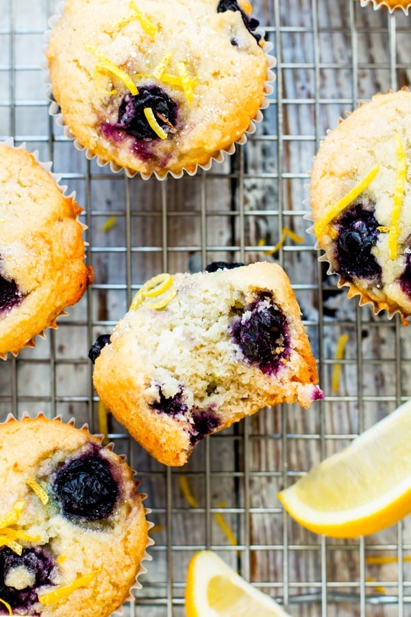 A gluten-free lemon muffin with a bite indention on a cooling rack.