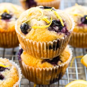 Healthy lemon muffins with blueberries stacked on top of each other on a cooling rack.
